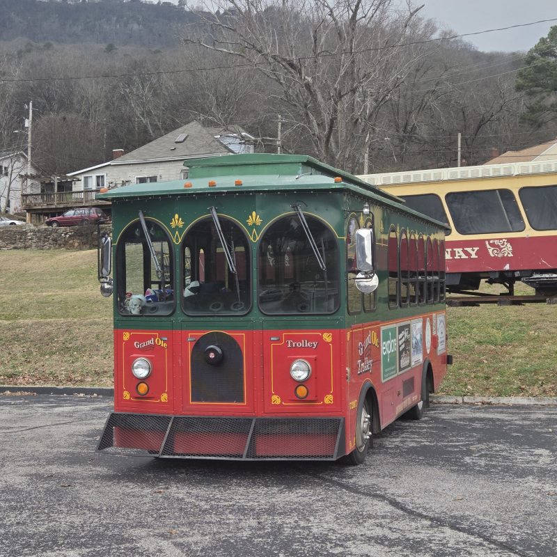 Colorful trolley parked, with trees and mountains in background.