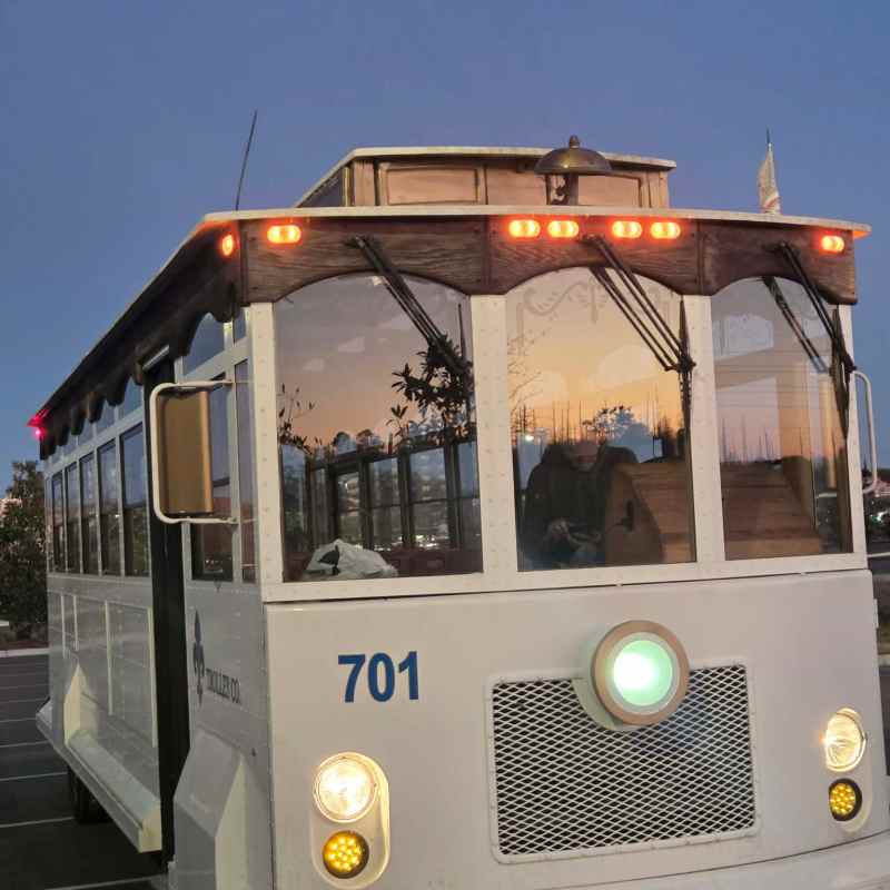 White vintage-style trolley with number 701 parked at dusk.